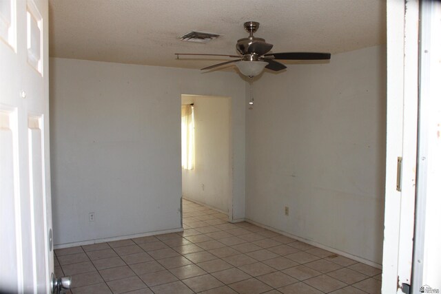 unfurnished room featuring ceiling fan, light tile patterned flooring, and a textured ceiling