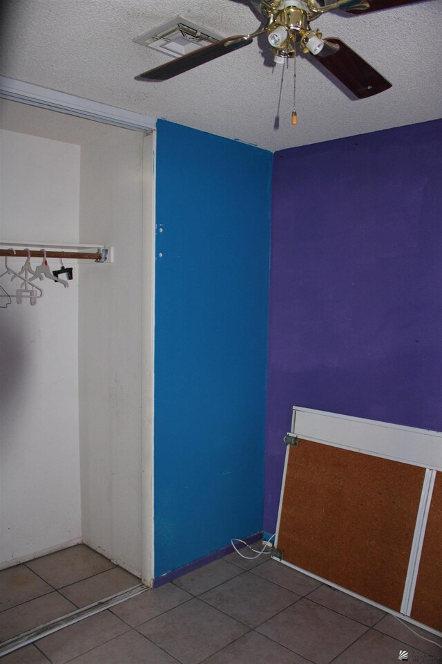 unfurnished bedroom featuring ceiling fan, tile patterned flooring, and a textured ceiling