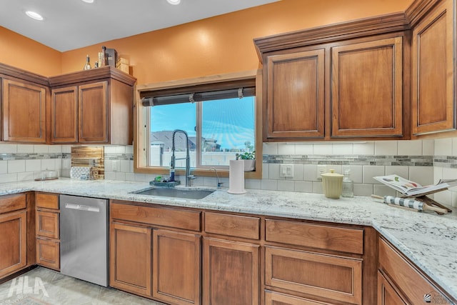 kitchen with light stone counters, dishwasher, sink, and tasteful backsplash