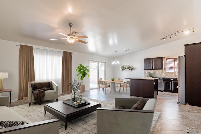 tiled living room with ceiling fan with notable chandelier and vaulted ceiling