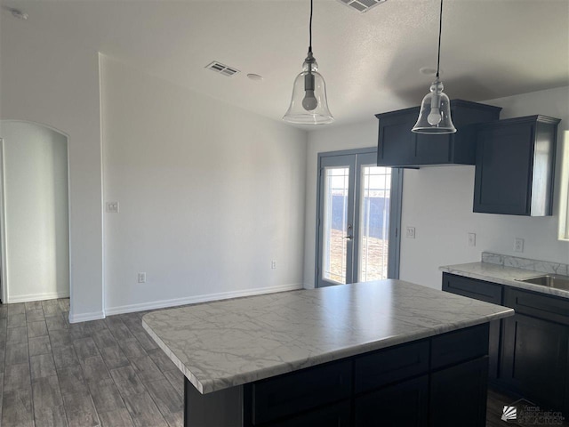 kitchen with decorative light fixtures, dark wood-type flooring, french doors, and a kitchen island