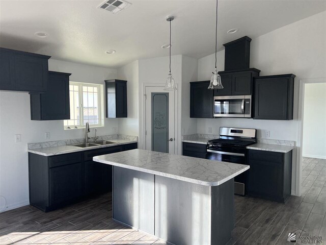 kitchen featuring pendant lighting, stainless steel appliances, a center island, and sink