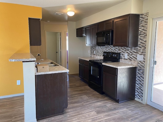 kitchen with backsplash, black appliances, sink, hardwood / wood-style flooring, and dark brown cabinetry