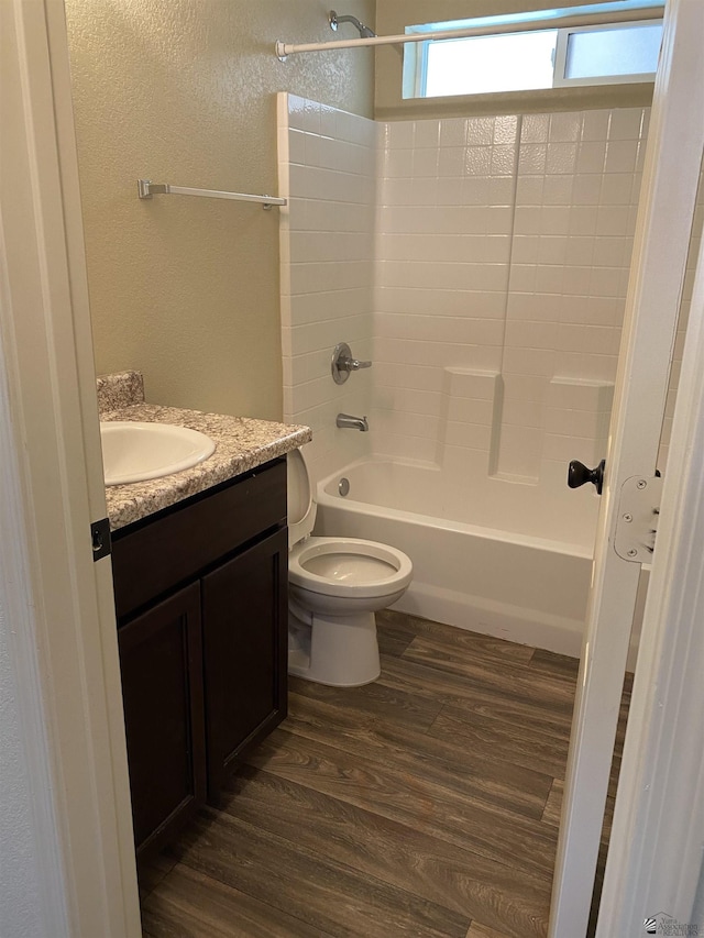 full bathroom with vanity, washtub / shower combination, wood-type flooring, and toilet