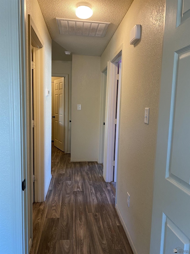 corridor featuring dark hardwood / wood-style floors and a textured ceiling