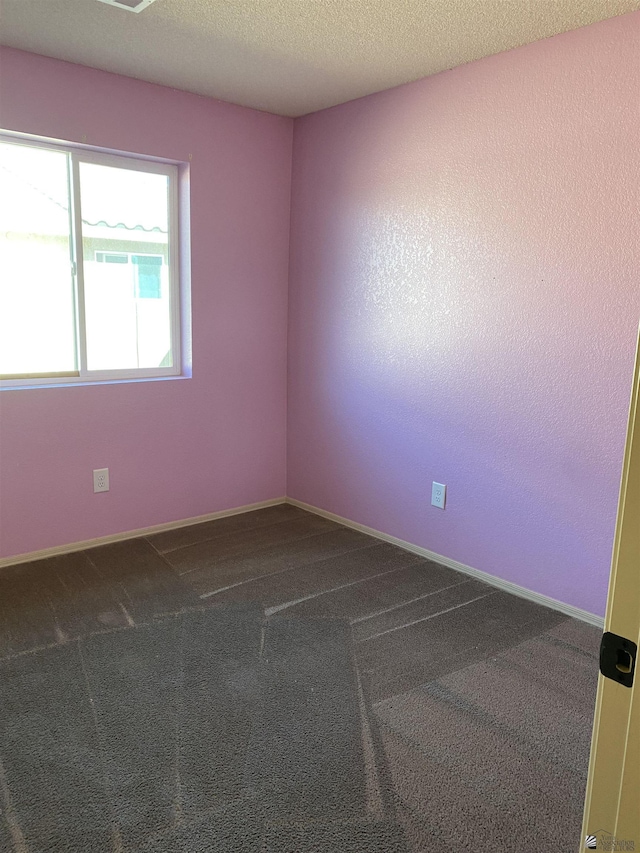 carpeted empty room with a textured ceiling