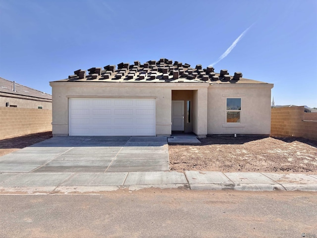 view of front of home with stucco siding, concrete driveway, a garage, and fence