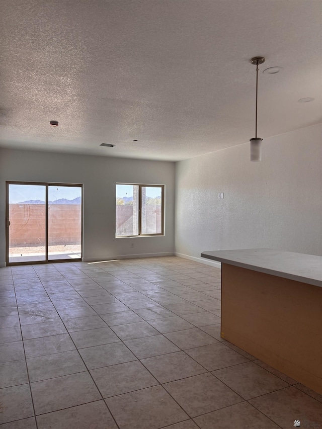 unfurnished room featuring baseboards, visible vents, a textured ceiling, tile patterned floors, and a textured wall