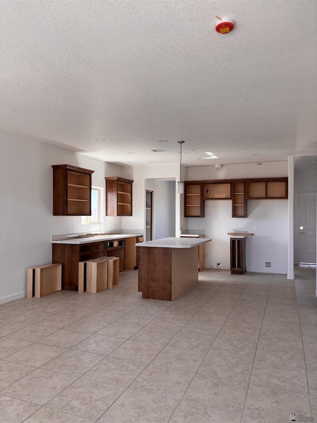 kitchen with open shelves, a textured ceiling, a center island, and light countertops