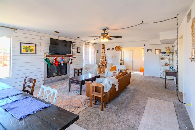 living room with ceiling fan, wood walls, and light carpet