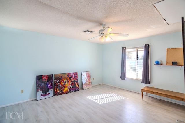 recreation room featuring ceiling fan, light hardwood / wood-style flooring, and a textured ceiling