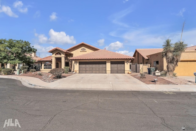 mediterranean / spanish home featuring concrete driveway, an attached garage, a tiled roof, and stucco siding