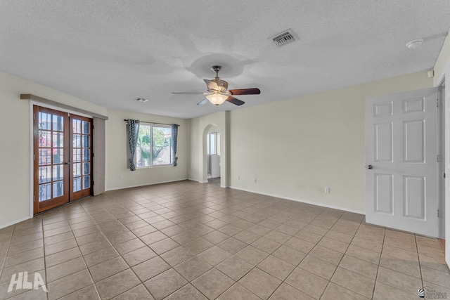 empty room with light tile patterned floors, arched walkways, visible vents, a ceiling fan, and french doors