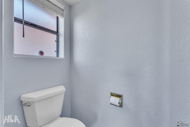 bathroom with a textured wall and toilet