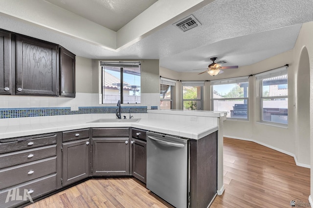 kitchen with dishwasher, dark brown cabinets, a sink, and visible vents