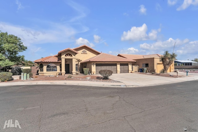 mediterranean / spanish-style house featuring driveway, a tiled roof, an attached garage, and stucco siding