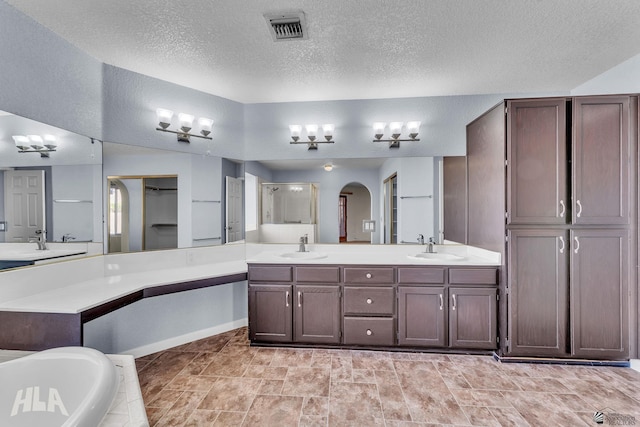 bathroom with double vanity, visible vents, a washtub, a shower stall, and a sink