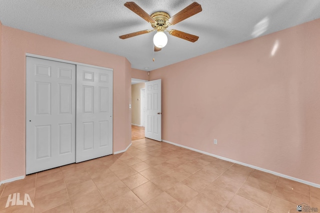 unfurnished bedroom with a textured ceiling, baseboards, and a closet