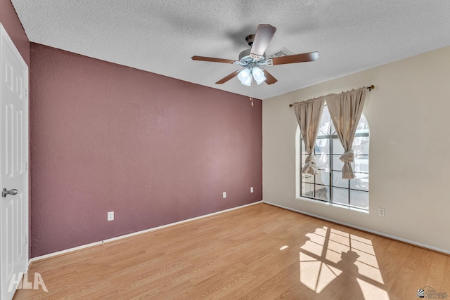 unfurnished room with a textured ceiling, ceiling fan, light wood finished floors, and baseboards