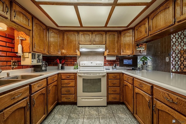 kitchen with under cabinet range hood, brown cabinetry, white range with electric cooktop, and light countertops