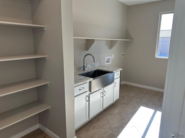 kitchen with sink, light tile patterned floors, light stone countertops, and white cabinets