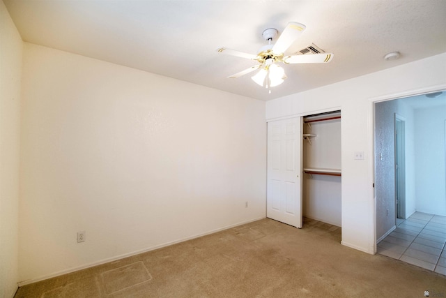 unfurnished bedroom featuring ceiling fan, a closet, and light carpet