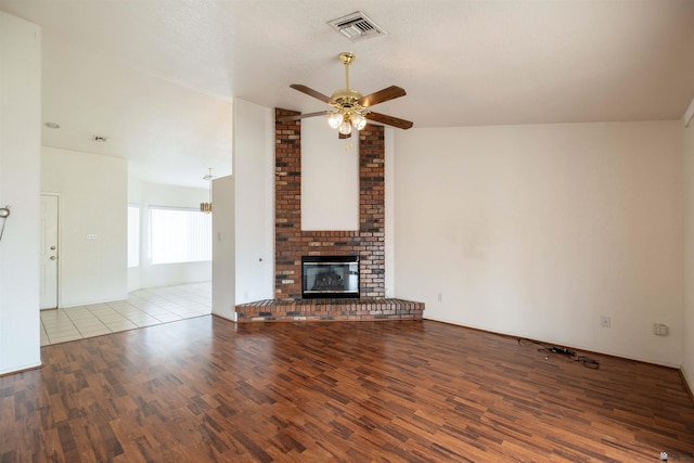 unfurnished living room featuring vaulted ceiling, ceiling fan, light hardwood / wood-style floors, a brick fireplace, and a textured ceiling