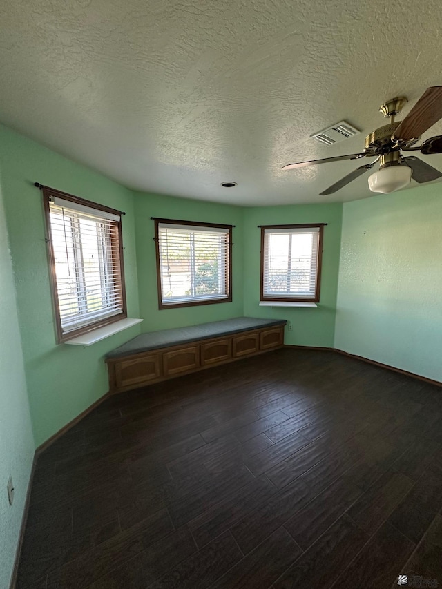 empty room with ceiling fan, dark hardwood / wood-style floors, and a textured ceiling