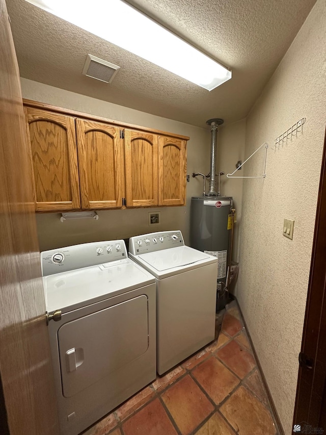 laundry area with independent washer and dryer, gas water heater, a textured ceiling, and cabinets