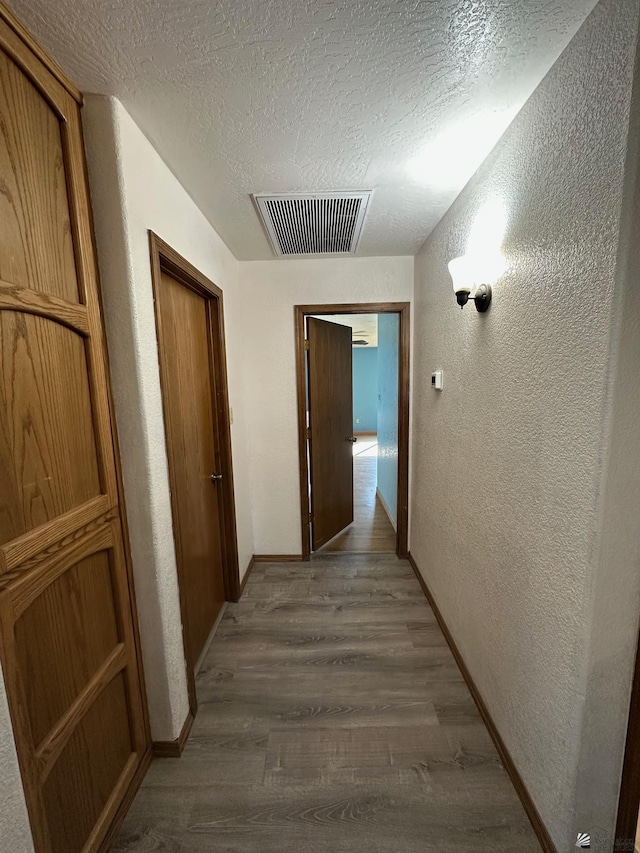 hall with a textured ceiling and dark hardwood / wood-style floors