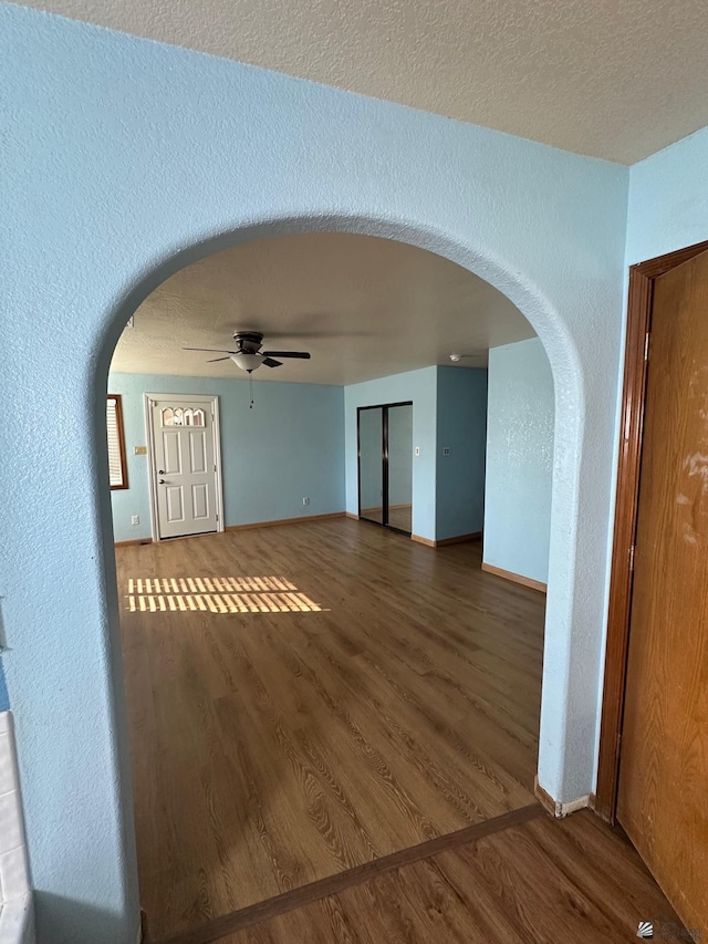 unfurnished living room featuring ceiling fan and dark wood-type flooring