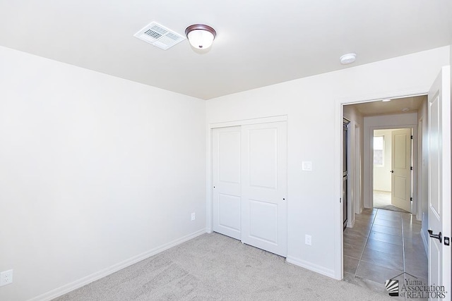 unfurnished bedroom with visible vents, baseboards, a closet, and carpet flooring