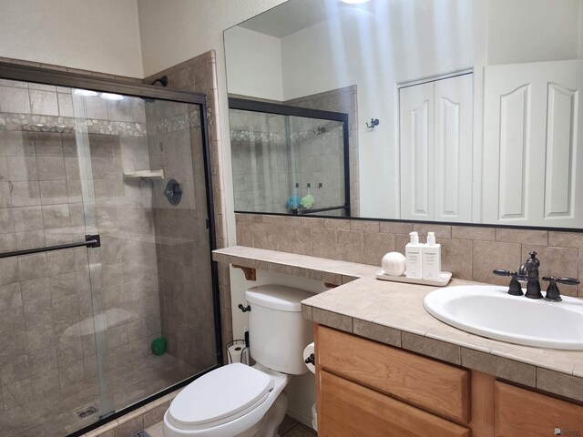 bathroom with vanity, toilet, a shower with door, and tasteful backsplash