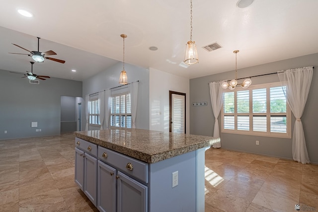 kitchen featuring a kitchen island, pendant lighting, and ceiling fan with notable chandelier