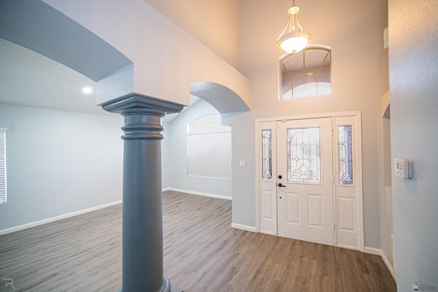 foyer with a towering ceiling, baseboards, and wood finished floors