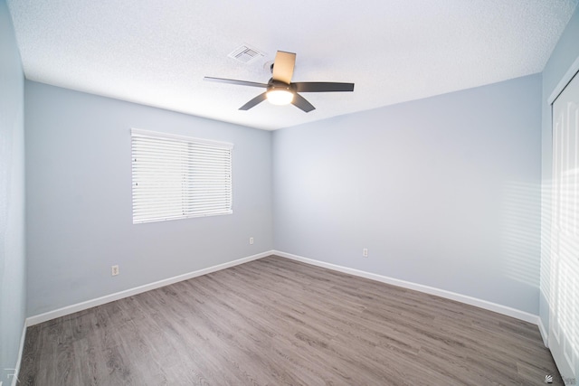 unfurnished room with visible vents, a textured ceiling, baseboards, and wood finished floors