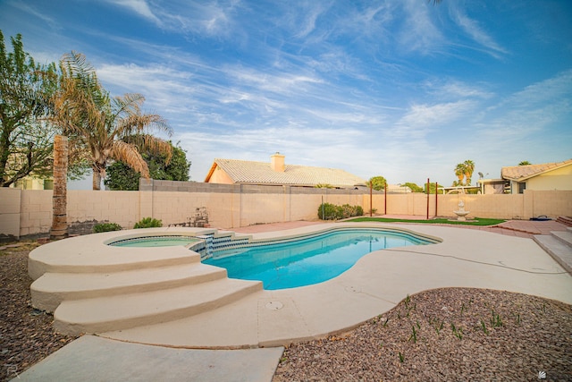 view of swimming pool featuring a patio area, a fenced backyard, and a pool with connected hot tub