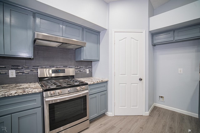 kitchen featuring stainless steel range with gas cooktop, decorative backsplash, gray cabinetry, light wood-type flooring, and under cabinet range hood