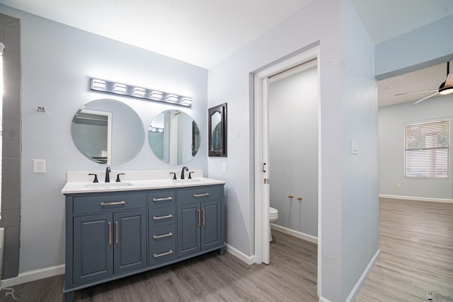 bathroom featuring toilet, a sink, baseboards, and wood finished floors