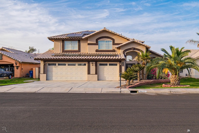 mediterranean / spanish-style house featuring a garage, concrete driveway, solar panels, and stucco siding