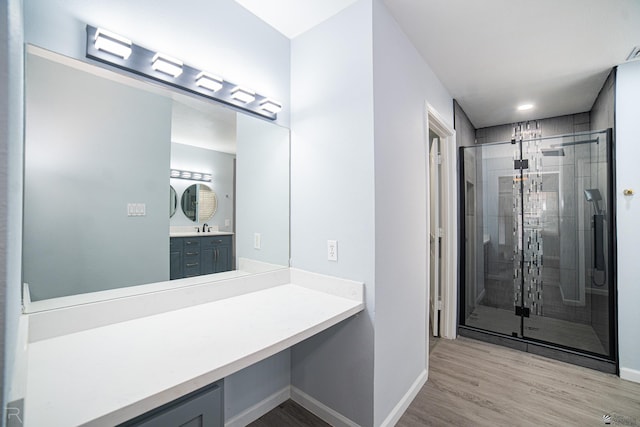 bathroom with a shower stall, baseboards, wood finished floors, and vanity