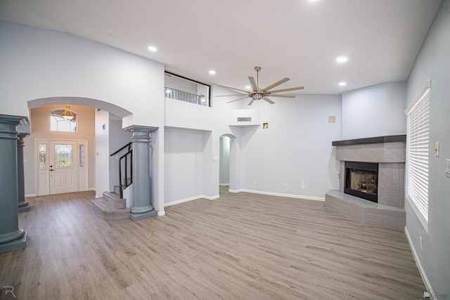 unfurnished living room featuring arched walkways, a brick fireplace, recessed lighting, and wood finished floors