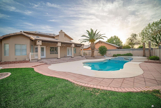 view of swimming pool with a yard, a pool with connected hot tub, a fenced backyard, and a patio