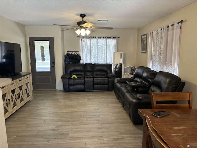 living room with a textured ceiling and ceiling fan