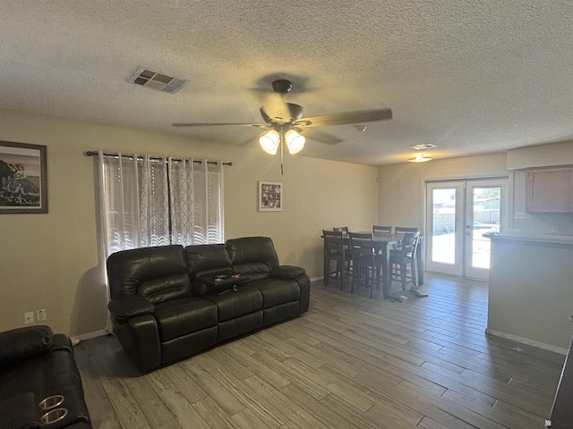 living room with hardwood / wood-style flooring, ceiling fan, and a textured ceiling