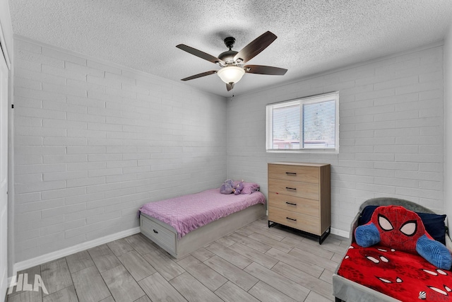 bedroom featuring a textured ceiling, brick wall, a ceiling fan, and wood tiled floor