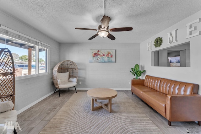 living room with a textured ceiling, ceiling fan, baseboards, and wood tiled floor