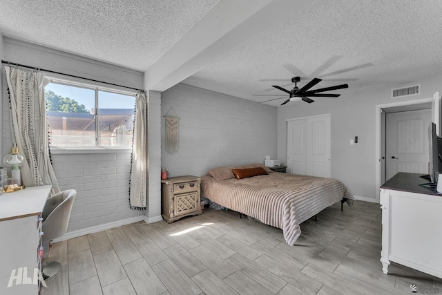 bedroom featuring wood finish floors, visible vents, ceiling fan, a textured ceiling, and baseboards