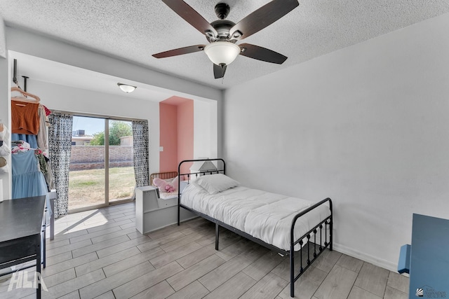 bedroom featuring a ceiling fan, wood tiled floor, and a textured ceiling