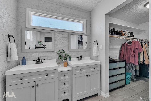 full bathroom featuring a textured ceiling, double vanity, wood finished floors, and a sink